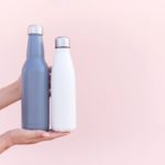 Eco friendly reusabel water bottle. Female hands holding two sustainable eco friendly water bottles1 blue stainless steel water bottle and 1 white stainless steel water bottle
