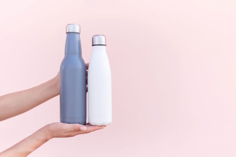Eco friendly reusabel water bottle. Female hands holding two sustainable eco friendly water bottles1 blue stainless steel water bottle and 1 white stainless steel water bottle